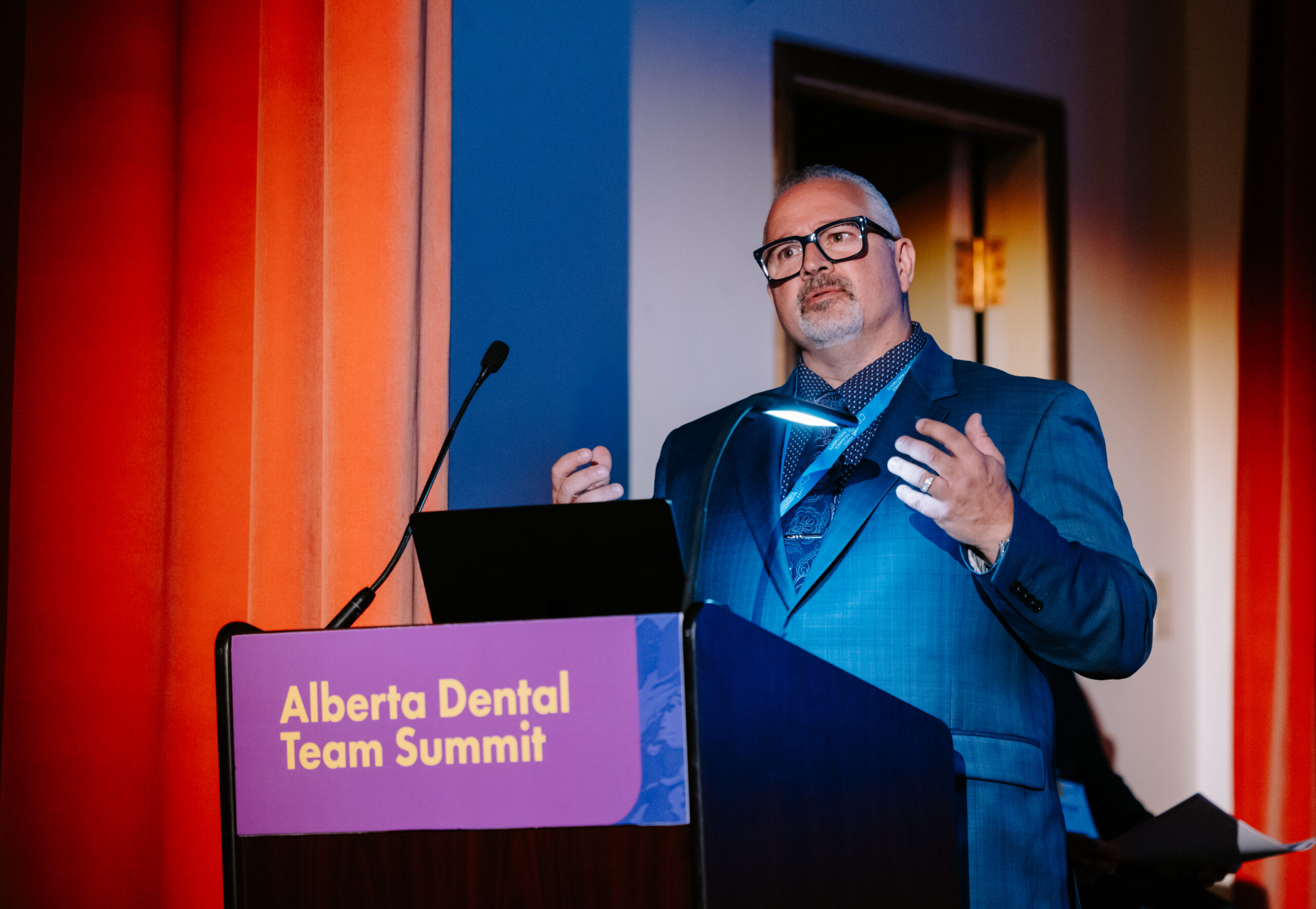 A speaker stands behind a podium, engaging his audience at the 2025 Summit